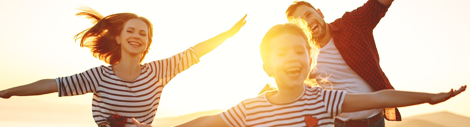 Familie rennt während dem Sonnenuntergang über ein Feld